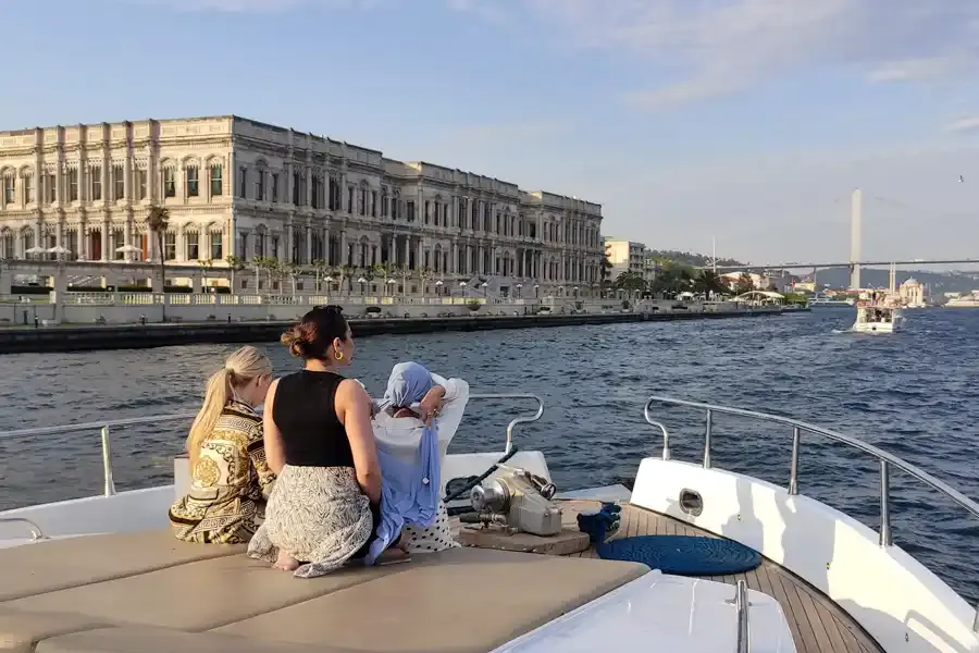 Guests on the bow of a private yacht passing Çırağan Palace