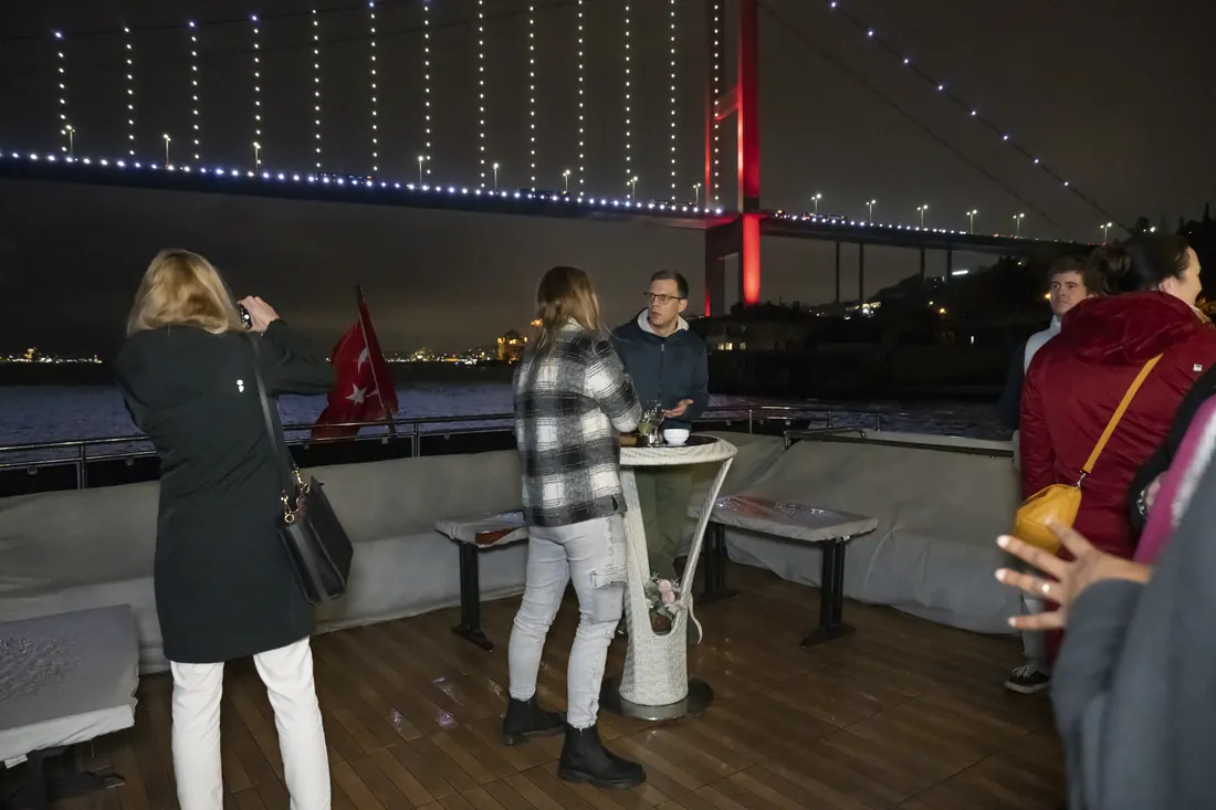 Guests on deck with the Bosphorus Bridge lit up at night