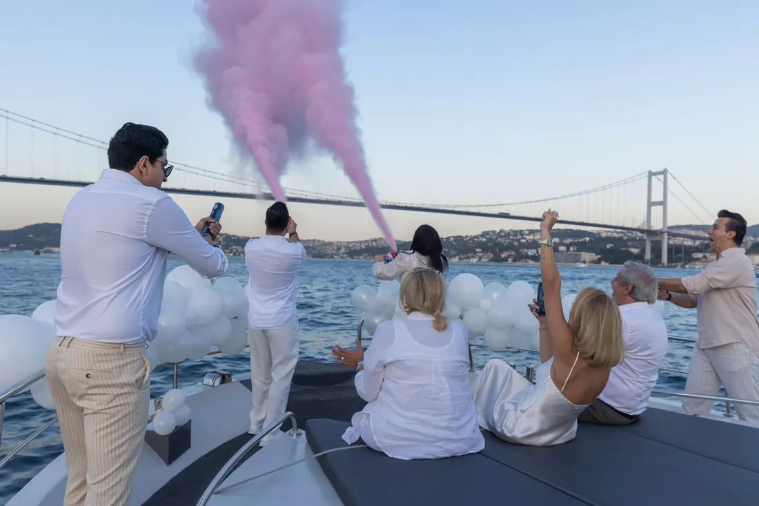 Guests celebrating with pink smoke on a yacht near the Bosphorus Bridge