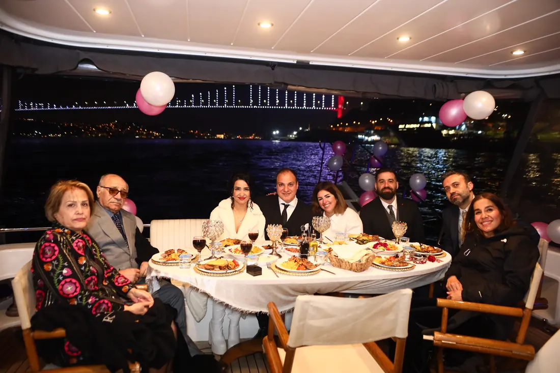 Family celebration dinner on a yacht with the bridge lit up