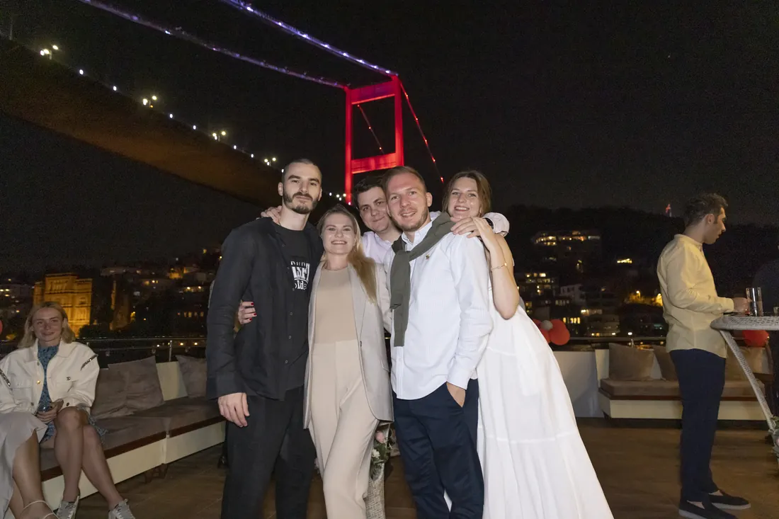 Friends at a yacht party under the Bosphorus Bridge at night