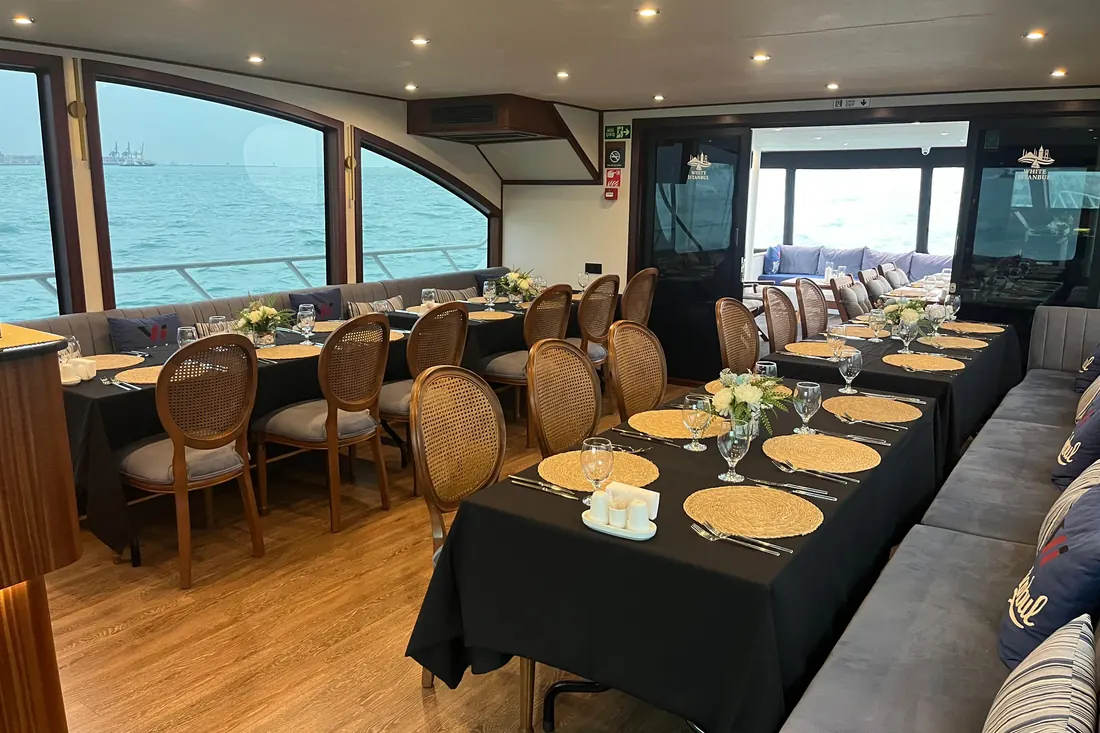 Dinner tables set with black linen in a yacht saloon