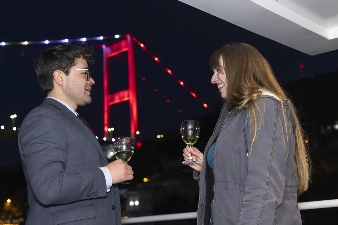 Couple raising a toast with the Bosphorus Bridge at night