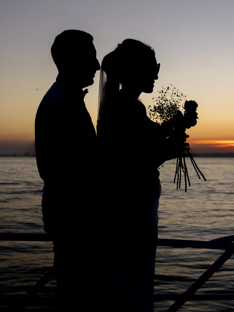 Newlyweds silhouetted at sunset on a yacht
